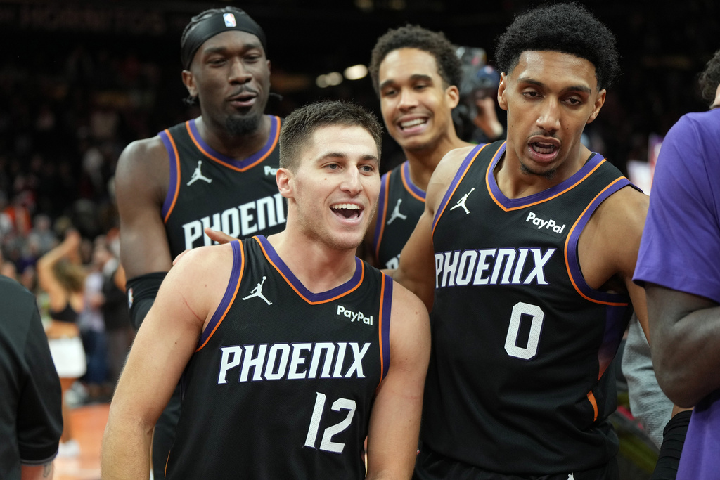 Phoenix Suns guard Collin Gillespie (12) celebrates with teammates after hitting the winning shot against the Minnesota Timberwolves during the second half of an NBA Cup basketball game, Friday, Nov. 21, 2025, in Phoenix. (AP Photo/Rick Scuteri)