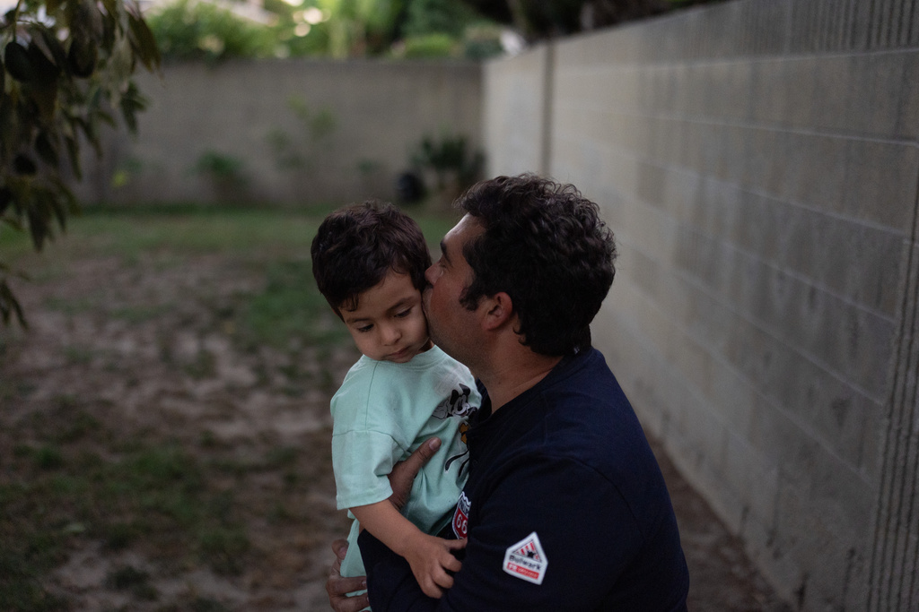 Wilfredo Cruz, an oil worker at the Phillips 66 Los Angeles Refinery Wilmington Plant, kisses his son, Cassian, while playing in their backyard Tuesday, Sept. 30, 2025, in Cerritos, Calif. (AP Photo/Jae C. Hong)