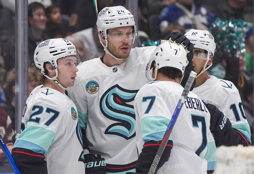 Seattle Kraken's Jamie Oleksiak (24), Berkly Catton (27), Jordan Eberle (7) and Matty Beniers (10) celebrate Oleksiak's goal during the second period of an NHL hockey game against the Vancouver Canucks, in Vancouver, on Saturday, March 14, 2026. (Darryl Dyck/The Canadian Press via AP)