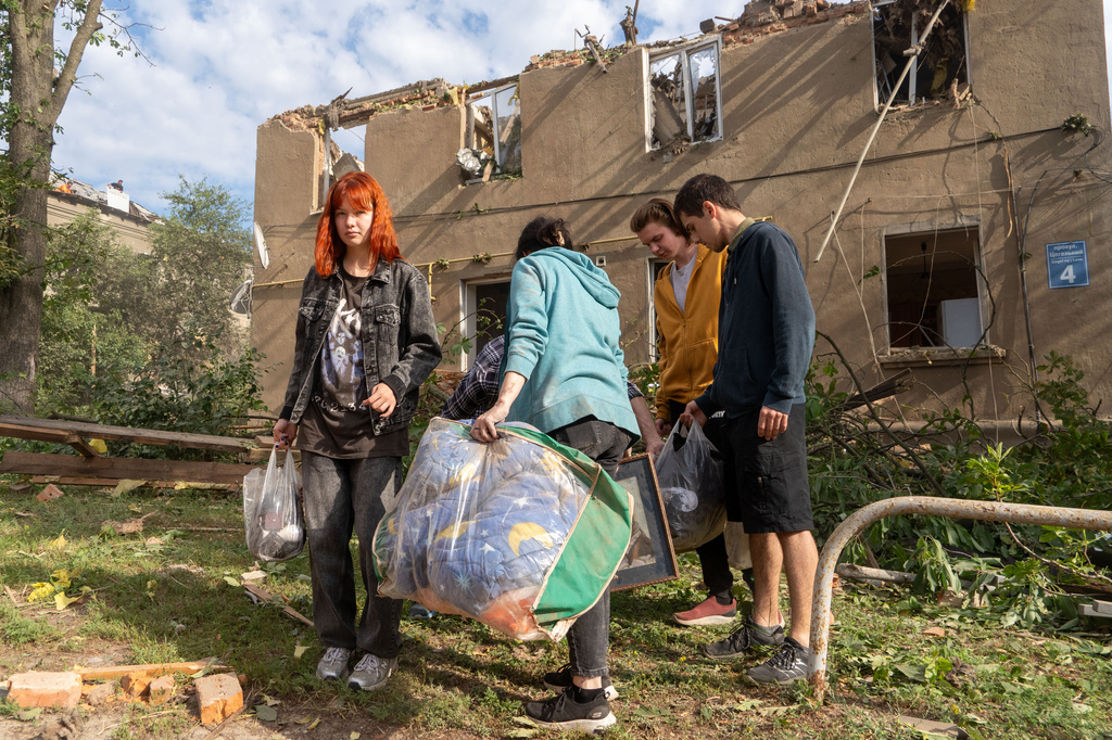 People carry their belongings as they leave their home after a Russian missile hit a residential building during an air attack in Kharkiv, Ukraine, Saturday, June 20, 2026. (AP Photo/Andrii Marienko)