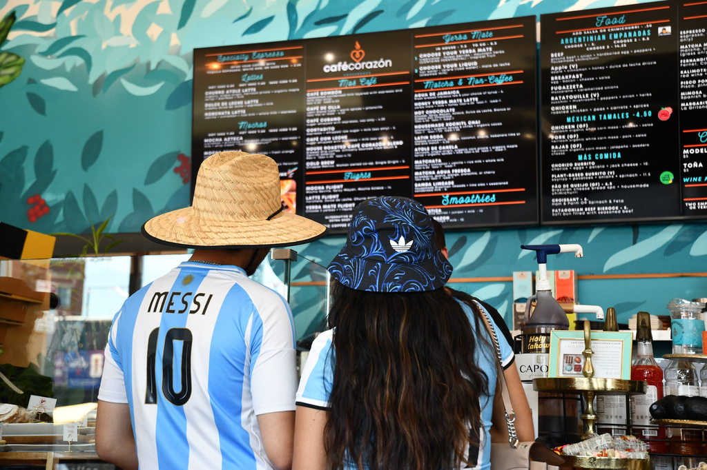 Fans wearing Argentina national team jerseys look at a menu of drinks at Cafe Corazon, Monday, June 15, 2026, in Kansas City, Mo. (AP Photo/Kristin M. Hall)