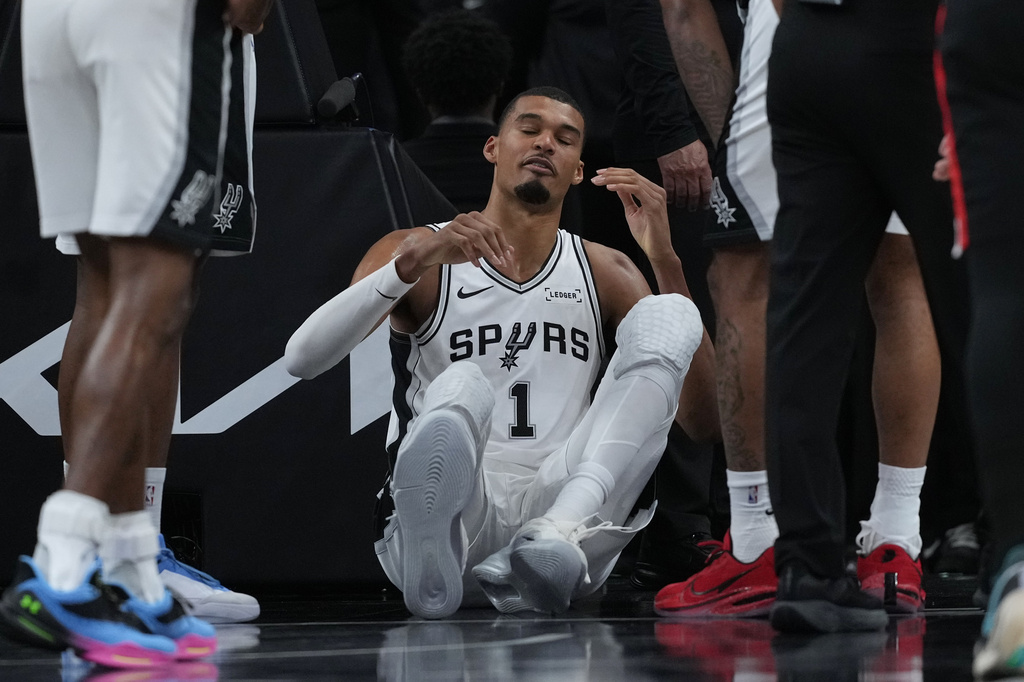 San Antonio Spurs forward Victor Wembanyama (1) sits on the court after a hard fall during the first half in Game 2 of a first-round NBA playoffs basketball series against the Portland Trail Blazers in San Antonio, Tuesday, April 21, 2026. (AP Photo/Eric Gay)