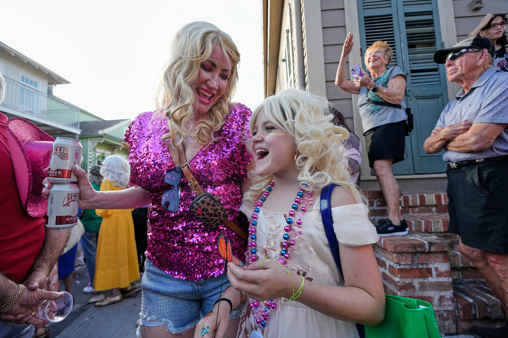 Adrienne Hery and her daughter June Hery, 9, watch as members of the Krewe of Dolly lead a second line parade in commemoration of the life of Dolly Parton through the French Quarter Friday, Sept. 25, 2026, in New Orleans. (AP Photo/Gerald Herbert)
