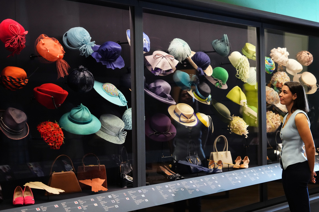 A member of the Royal Collection Trust staff looks towards hats, bags and shoes worn by Princess Elizabeth, on display at 'Queen Elizabeth II: Her Life in Style' exhibition, to mark the centenary of the late queen's birth, at The King's Gallery at Buckingham Palace in London, Thursday, April 9, 2026. (AP Photo/Kirsty Wigglesworth)