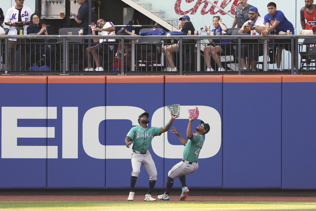 Seattle Mariners outfielder Randy Arozarena, left, and Julio Rodríguez, right, reach for a flyout hit by New York Mets' Juan Soto during the fifth inning of a baseball game, Saturday, Aug. 16, 2025, in New York. (AP Photo/Heather Khalifa)