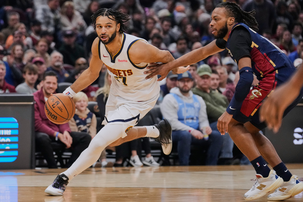 Denver Nuggets guard Jamal Murray (27) drives past Cleveland Cavaliers guard Darius Garland, right, in the first half of an NBA basketball game Friday, Jan. 2, 2026, in Cleveland. (AP Photo/Sue Ogrocki)