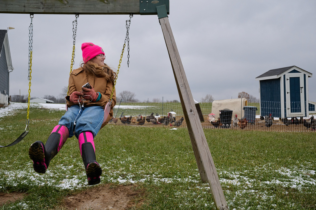 Blakeley Pyles listens to music on a swing after she helped her parents work a herd of calves on their farm in Henry County, Ky., Saturday, Dec. 13, 2025. (AP Photo/Michael Swensen)