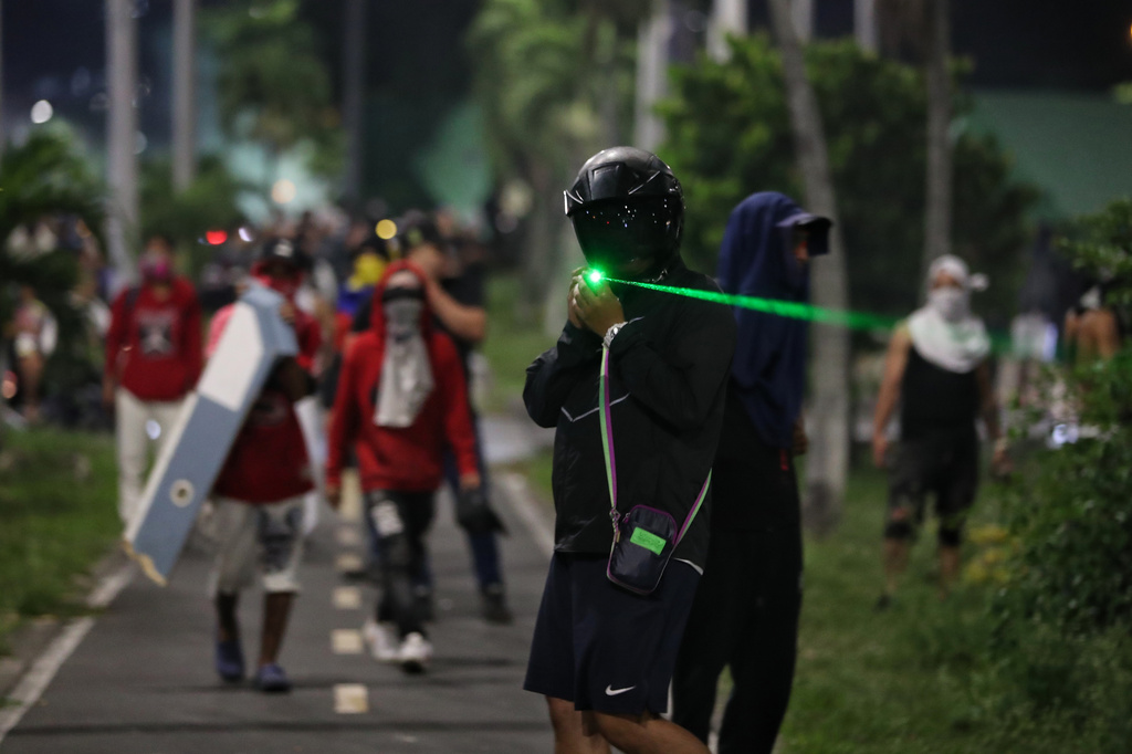 A supporter of presidential candidate Ivan Cepeda of the ruling Historic Pact coalition points a laser at police during a protest after election results showed him trailing in the runoff election in Cali, Colombia, Sunday, June 21, 2026. (AP Photo/Santiago Saldarriaga)