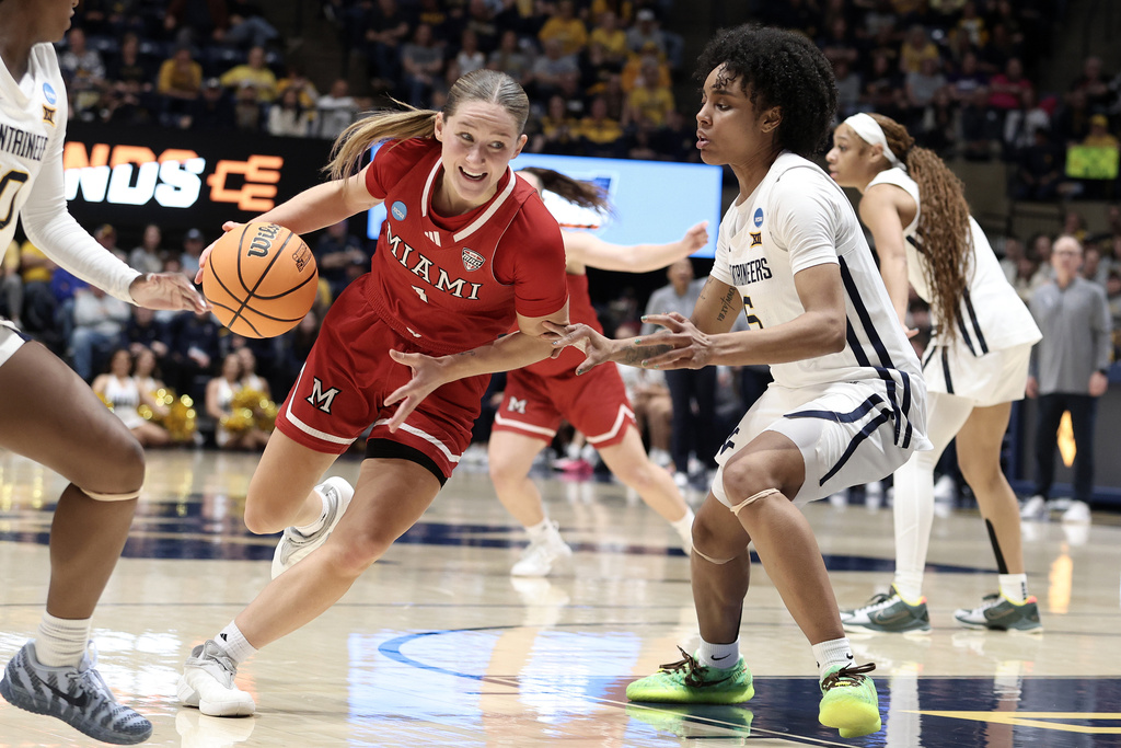 Miami (Ohio) guard Amber Scalia (1) dives past Virginia guard Sydney Shaw (5) in the second half in the first round of the NCAA college basketball tournament, Saturday, March 21, 2026, in Morgantown, W.Va. (AP Photo/Kathleen Batten)