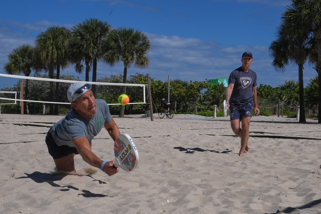Robert Minion and his friend James Denburg of MA., take advantage of the cool weather to play beach tennis Thursday, Jan. 29, 2026, in Miami Beach, Fla. (AP Photo/Marta Lavandier)