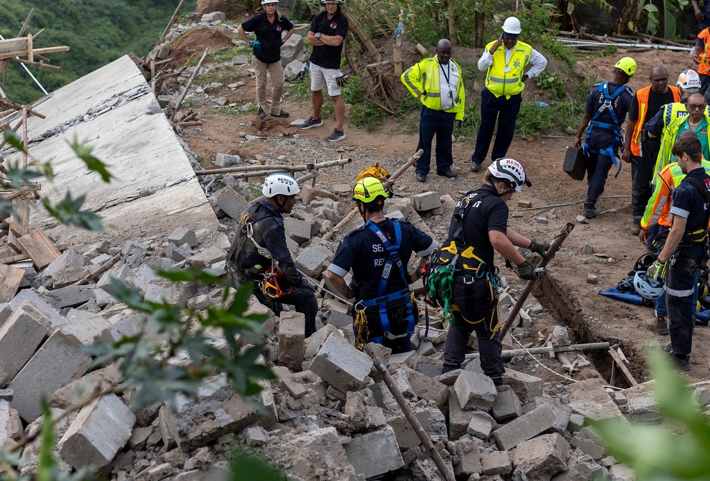 Rescuers search for victims following multi-story building that was under construction collapsed on a temple below it, near the town of Verulam, north of the east coast city of Durban, South Africa, Friday, Dec. 12, 2025. (AP Photo)