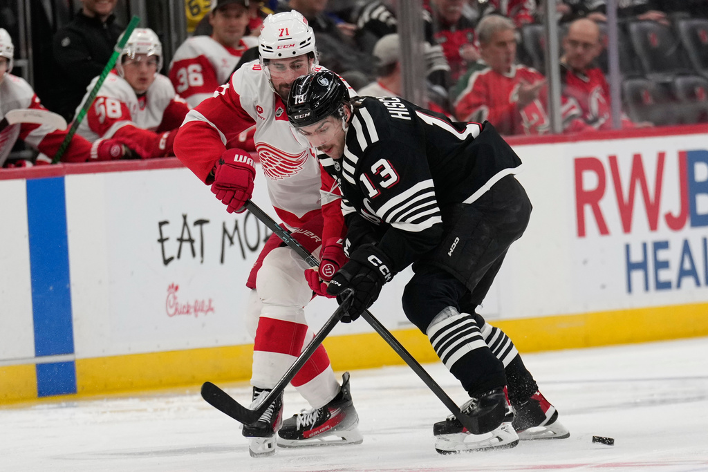 Detroit Red Wings' Dylan Larkin, left, and New Jersey Devils' Nico Hischier battle for the puck during the second period of an NHL hockey game in Newark, N.J., Monday, Nov. 24, 2025. (AP Photo/Seth Wenig)