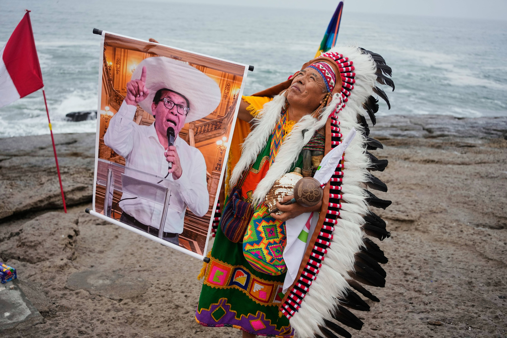 A shaman performs a ritual holding a poster of presidential candidate Roberto Sanchez on Herradura beach in Lima, Peru, Monday, June 1, 2026, ahead of the presidential runoff election. (AP Photo/Martin Mejia)