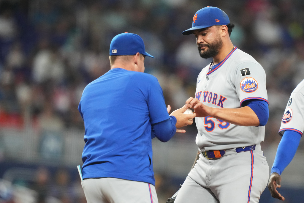 New York Mets starting pitcher Sean Manaea, right, hands the ball to New York Mets manager Carlos Mendoza after being relieved during the second inning of a baseball game against the Miami Marlins, Sunday, Sept. 28, 2025, in Miami. (AP Photo/Lynne Sladky)