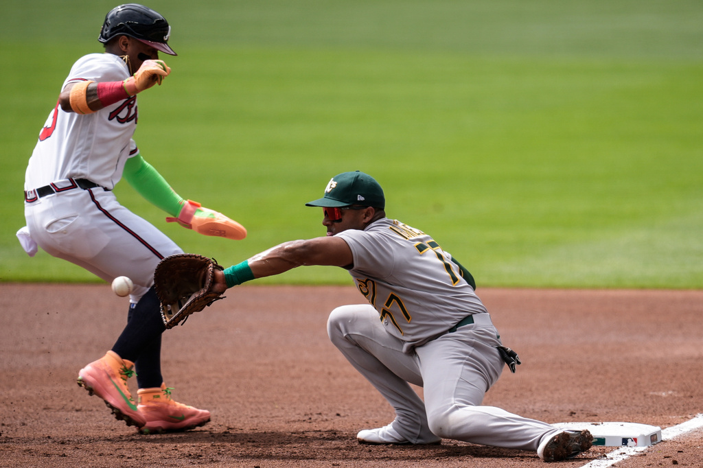 Athletics third baseman Andy Ibáñez (77) makes the tag on Atlanta Braves' Ronald Acuña Jr. (13) in the first inning of a baseball game, Wednesday, April 1, 2026, in Atlanta. (AP Photo/Mike Stewart)
