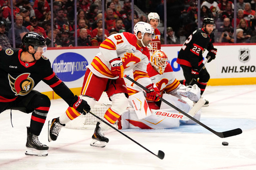 Calgary Flames' Nazem Kadri (91) gets the puck out of the Flames end as Ottawa Senators' Shane Pinto (12) chases, during second period NHL hockey action in Ottawa, on Thursday, Oct. 30, 2025. (Justin Tang/The Canadian Press via AP) Calgary Flames' Nazem Kadri (91) gets the puck out of the Flames end as Ottawa Senators' Shane Pinto (12) chases, during second period NHL hockey action in Ottawa, on Thursday, Oct. 30, 2025. (Justin Tang/The Canadian Press via AP)