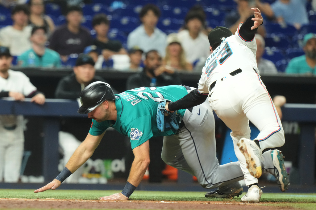 Miami Marlins relief pitcher Calvin Faucher (53 ) tags out Seattle Mariners' Cal Raleigh during the eighth inning of a baseball game Tuesday, July 7, 2026, in Miami. (AP Photo/Marta Lavandier)