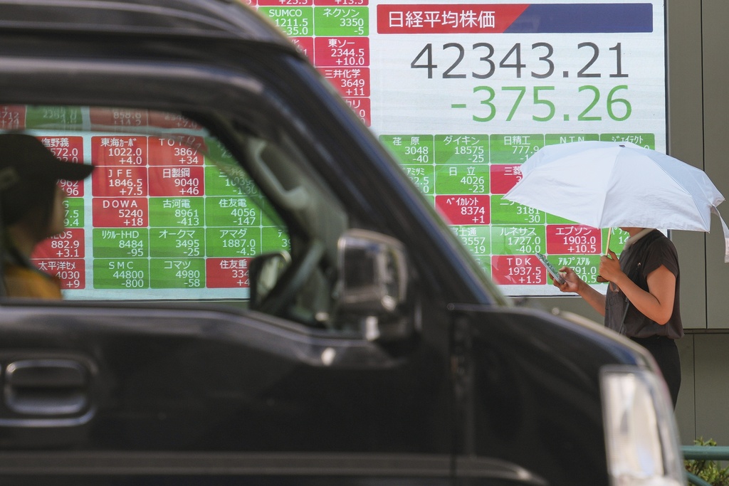 A person walks in front of an electronic stock board showing Japan's Nikkei index at a securities firm Monday, Sept. 1, 2025, in Tokyo. (AP Photo/Eugene Hoshiko)