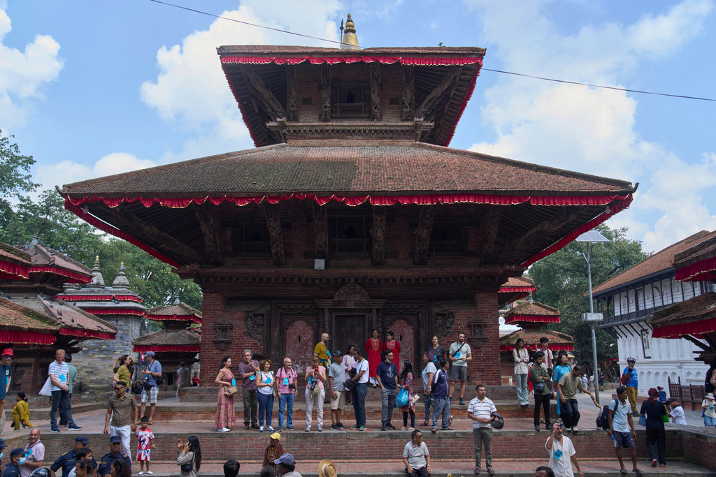 Tourists watch as Nepal's newly appointed living goddess, Kumari Aryatara Shakya, is carried toward Kumari Ghar, the temple palace where she will be residing in Kathmandu, Nepal, Tuesday, Sept. 30, 2025. (AP Photo/Niranjan Shrestha)