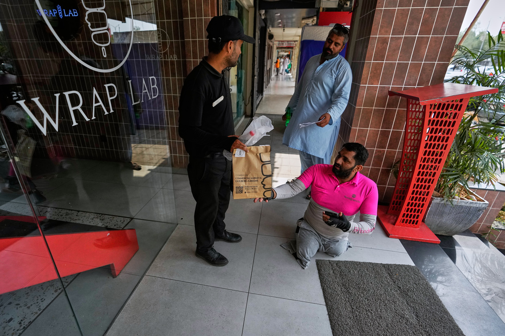 Hamza Ali, 28, who lost both legs in a road accident, collects a meal order from a food outlet to deliver to a customer in Islamabad, Pakistan, Friday, July 17, 2026. (AP Photo/Anjum Naveed)