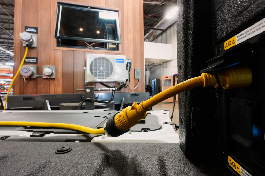 A one-foot long adapter is shown connected to a 240-volt outlet onboard a Ford F-150 King Ranch on Wednesday, July 22, 2026, in Southgate, Mich. The adapter makes the vehicle compatible to plug into a longer, separate cable that connects to a transfer switch installed directly on one's electric meter. (AP Photo/Paul Sancya)