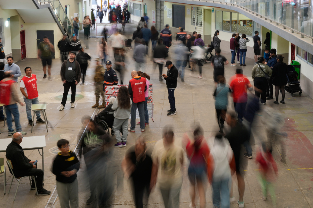 Voters walk at a polling station during the presidential runoff election in Santiago, Chile, Sunday, Dec. 14, 2025. (AP Photo/Matias Delacroix)