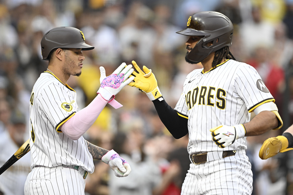 San Diego Padres' Fernando Tatis Jr., right, is congratulated by Manny Machado (13) after hitting a solo home run during the second inning of a baseball game against the Colorado Rockies Saturday, Sept. 13, 2025, in San Diego. (AP Photo/Denis Poroy)
