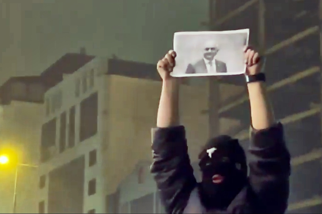 In this frame grab from video obtained by the AP outside Iran, a masked demonstrator holds a picture of Iran's Crown Prince Reza Pahlavi during a protest in Tehran, Iran, Friday, January. 9, 2026. (UGC via AP)