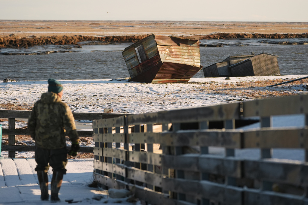 Harry Friend walks near an overturned shed and a home that sank into the river in Kwigillingok, Alaska, Monday, Oct. 27, 2025, after Typhoon Halong hit the region earlier in the month. (AP Photo/Lindsey Wasson)