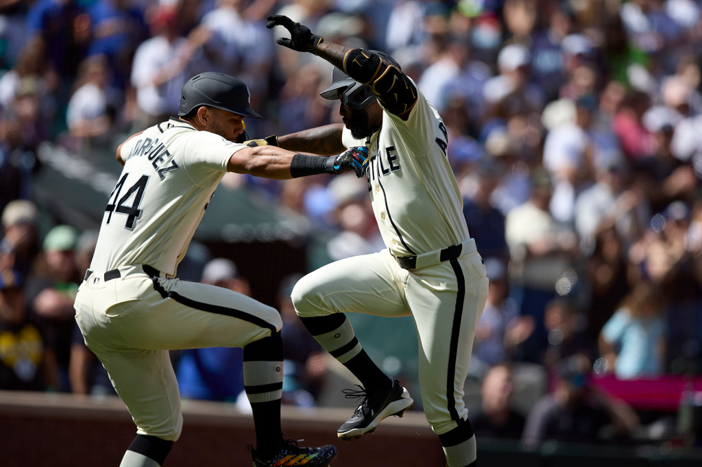 Seattle Mariners' Randy Arozarena, right, celebrates at home plate with Julio Rodríguez, left, after hitting a two-run home run off Texas Rangers starting pitcher MacKenzie Gore during the fifth inning in a baseball game Sunday, April 19, 2026, in Seattle. (AP Photo/John Froschauer)