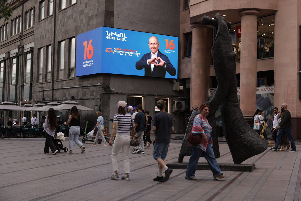 People walk along a street near a campaign advertisement for Armenian Prime Minister Nikol Pashinyan in Yerevan, Armenia, on Thursday, June 4, 2026. (AP Photo/Anthony Pizzoferrato)