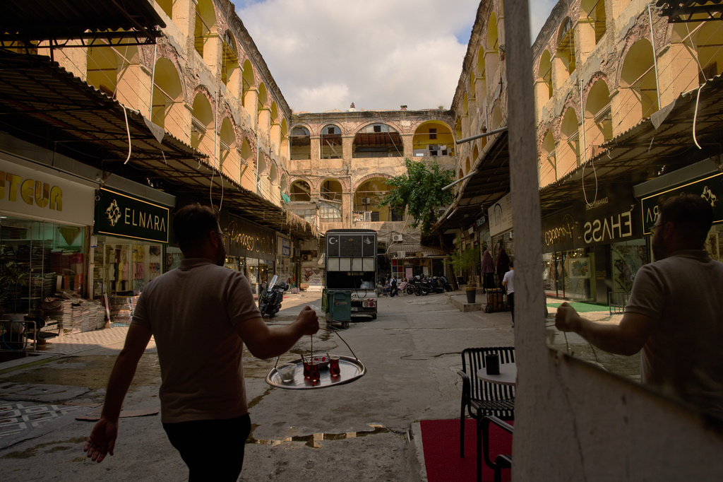 A waiter carries glasses of tea through the Buyukhan artisan quarter in Istanbul's Eminonu commercial district, Tuesday, Aug. 11, 2026. (AP Photo/Francisco Seco)