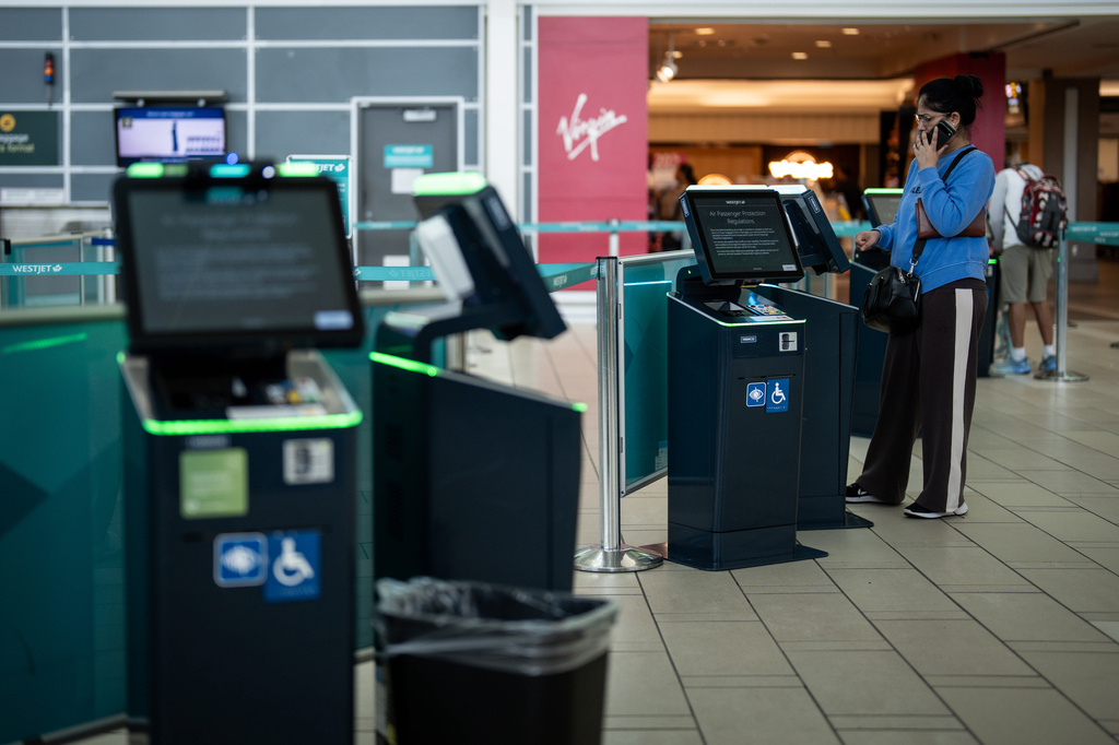 A traveller tries to check in for a cancelled WestJet flight at Vancouver International Airport in Richmond, British Columbia, Sunday, Aug. 2, 2026. (Ethan Cairns/The Canadian Press via AP)