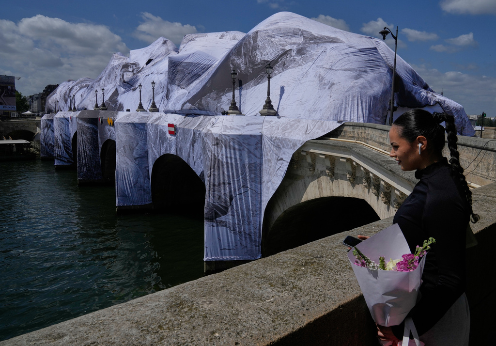 A woman looks at "The Pont Neuf Cave," an inflated art installation by French street artist JR, on Paris' oldest bridge, the Pont Neuf, Thursday, May 21, 2026, which will be open to the public from June 6-28. (AP Photo/Michel Euler)