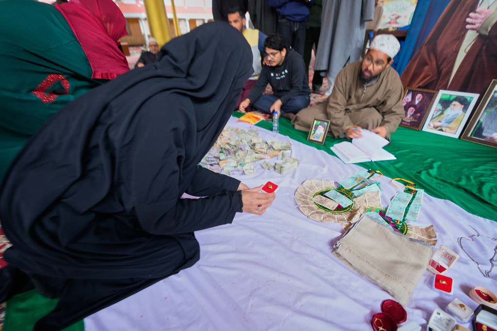 A Shiite Muslim woman donates her ring during a relief drive for Iran in Budgam, Indian-controlled Kashmir, Monday, March 23, 2026. (AP Photo/Mukhtar Khan)