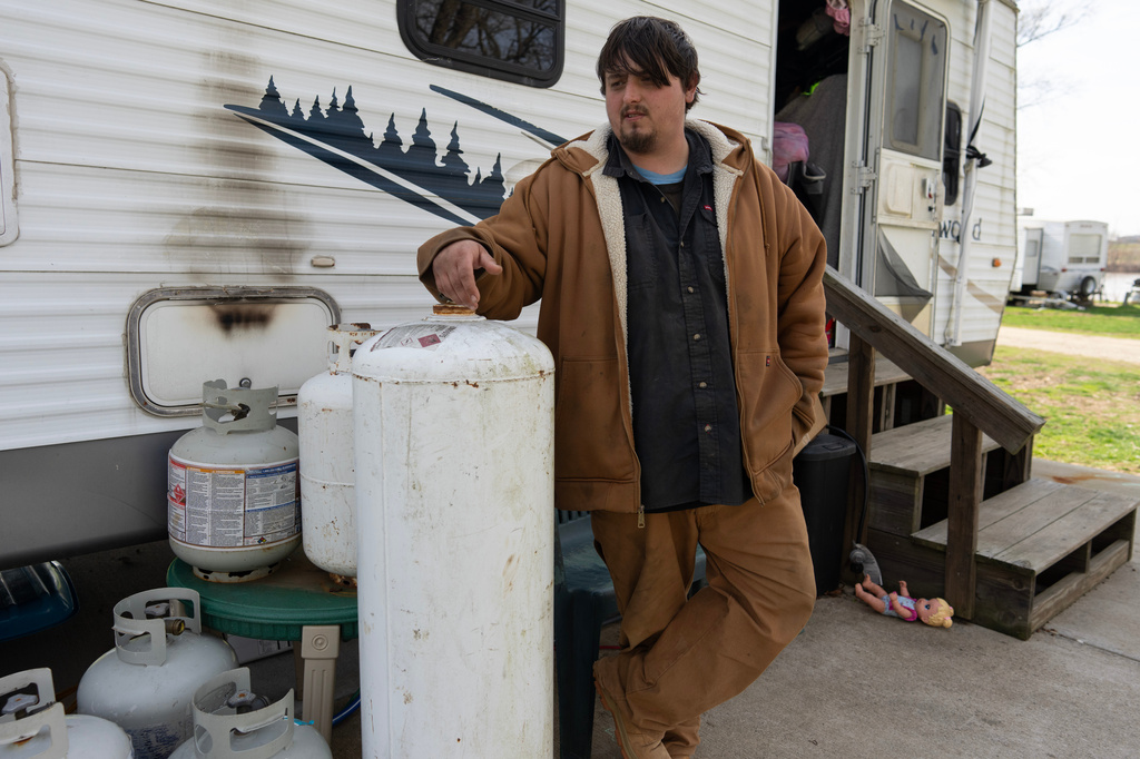 John White Jr., stands near propane tanks he uses for cooking outside his home at the Lock 24 RV Park and Campground in Racine, Ohio, Saturday, March 14, 2026, across the Ohio River from the coal-fired Mountaineer Power Plant, near New Haven, W.Va. (AP Photo/Carolyn Kaster)