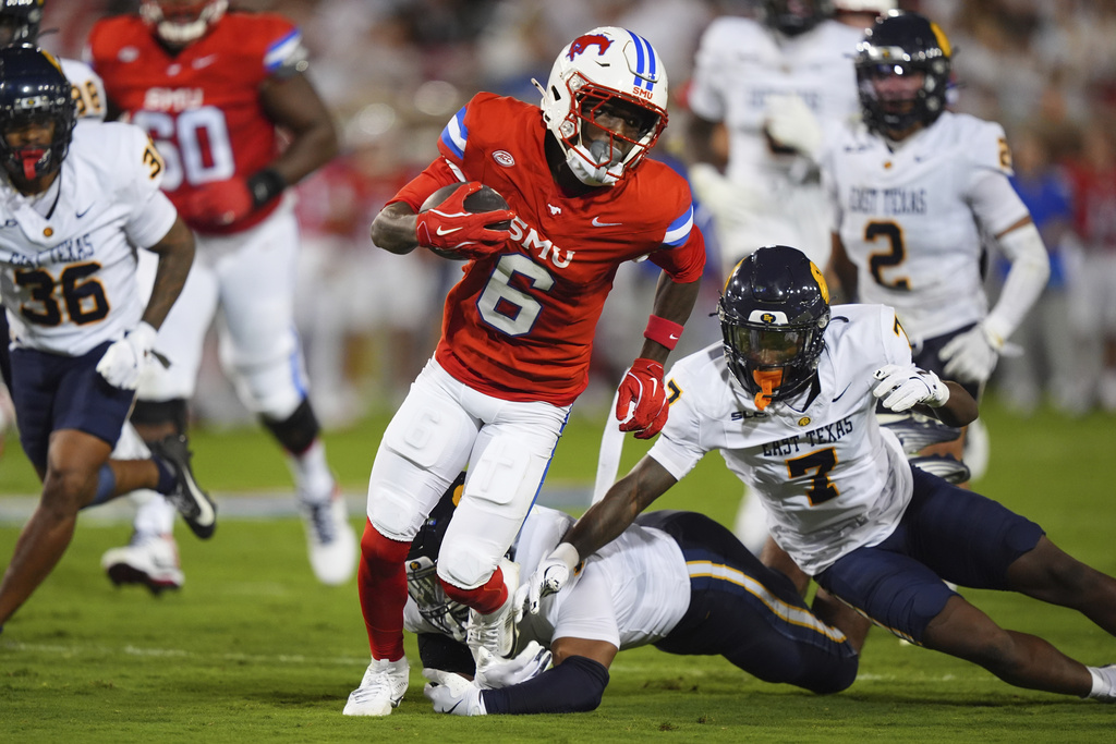 SMU running back Chris Johnson Jr. (6) breaks a tackle against East Texas A&M defensive back Javon Gillespie (7) and linebacker Koby-Sebasyen King, bottom, on the way to scoring a touchdown during the first half of an NCAA college football game, Saturday, Aug. 30, 2025, in Dallas. (AP Photo/LM Otero)