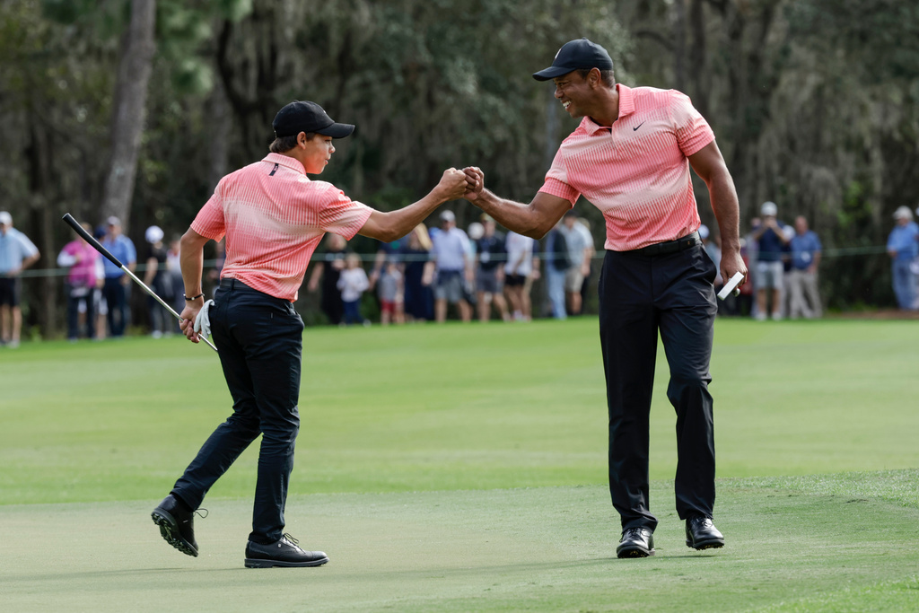 FILE - Tiger Woods, right and his son Charlie Woods bump fists on the ninth green during the first round of the PNC Championship golf tournament, Saturday, Dec. 17, 2022, in Orlando, Fla. (AP Photo/Kevin Kolczynski, File)