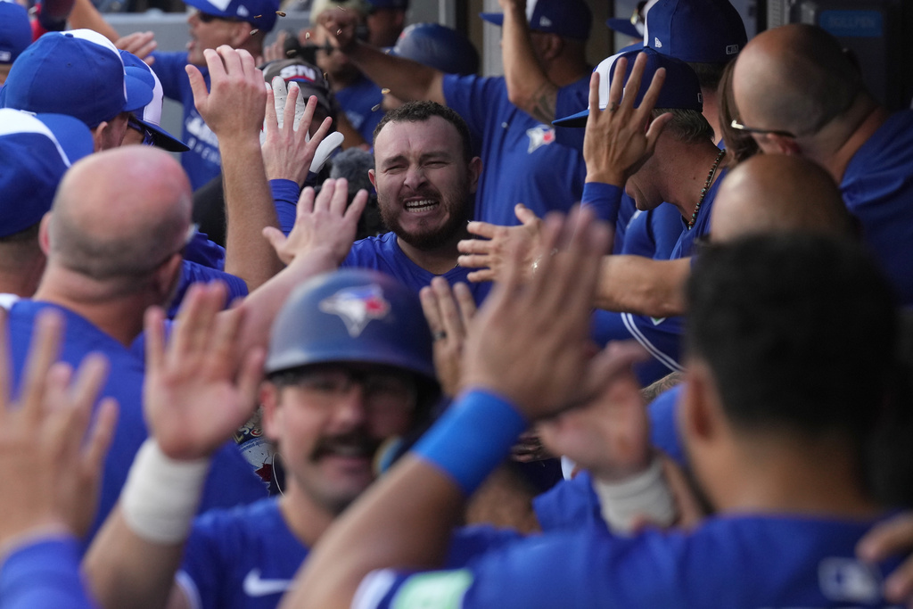 Toronto Blue Jays' Alejandro Kirk, center top, celebrates with teammates in the dugout after hitting a grand slam against the Tampa Bay Rays during first-inning baseball game action in Toronto, Sunday, Sept. 28, 2025. (Chris Young/The Canadian Press via AP)