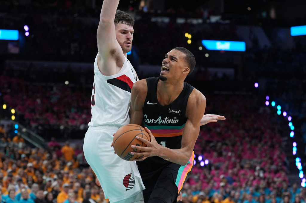 San Antonio Spurs forward Victor Wembanyama (1) drives against Portland Trail Blazers center Donovan Clingan (23) during the second half in Game 1 of a first-round NBA playoffs basketball series in San Antonio, Sunday, April 19, 2026. (AP Photo/Eric Gay)