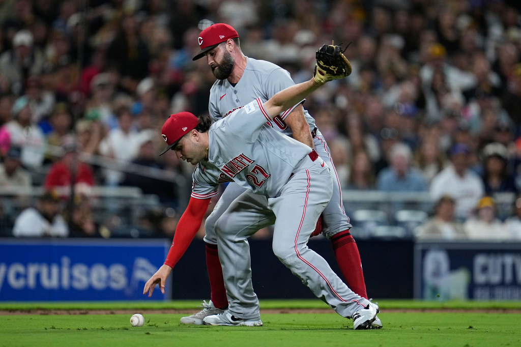 Cincinnati Reds first baseman Sal Stewart, front, drops the ball before throwing to first too late as San Diego Padres' Jase Bowen arrives safely for a bunt single while Cincinnati Reds pitcher Tejay Antone looks on, behind, during the seventh inning of a baseball game Monday, June 8, 2026, in San Diego. (AP Photo/Gregory Bull)