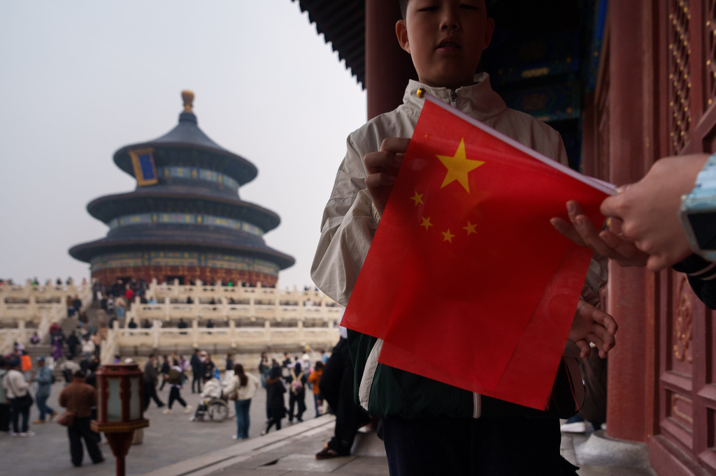 A child holds a Chinese national flag near the Hall of Prayer for Good Harvests at the Temple of Heaven in Beijing, China, Friday, April 3, 2026. (AP Photo/Vincent Thian)