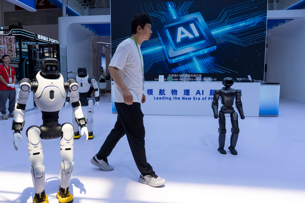 FILE- A worker passes by robots from Chinese company Lens at the China International Supply Chain Expo in Beijing on Monday, June 22, 2026. (AP Photo/Ng Han Guan, File)