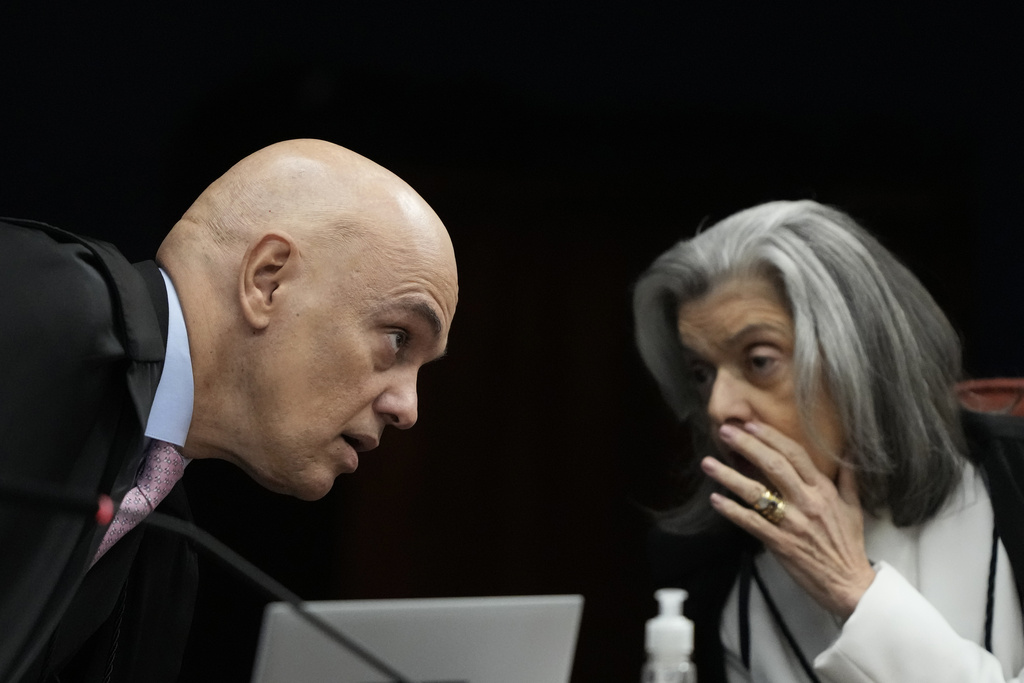 Supreme Court Justices Alexandre de Moraes, left, and Carmen Lucia speak during the verdict and sentencing phase of a trial for those charged in an alleged coup plot to keep former President Jair Bolsonaro in office after his 2022 election defeat, in Brasilia, Brazil, Tuesday, Sept. 9, 2025. (AP Photo/Eraldo Peres)