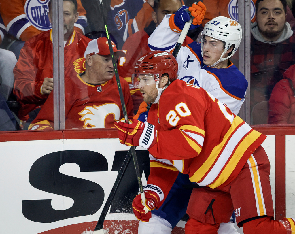 Edmonton Oilers' Ryan Nugent-Hopkins (93) is checked by Calgary Flames' Blake Coleman (20) during first-period NHL hockey game action in Calgary, Alberta, Saturday, Dec. 27, 2025. (Jeff McIntosh/The Canadian Press via AP)