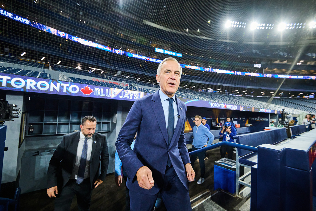 Canada's Prime Minister Mark Carney steps out of the Toronto Blue Jays' dugout as he visits the team on their media day ahead of the World Series against the Los Angeles Dodgers in Toronto, Thursday, Oct. 23, 2025. (Sammy Kogan/The Canadian Press via AP)