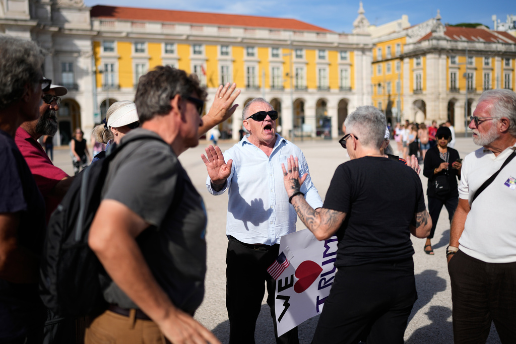A man carrying a pro-Trump poster argues with people participating in a No Kings protest organized by US citizens living in Portugal, in downtown Lisbon, Saturday, Oct. 18, 2025. (AP Photo/Armando Franca)