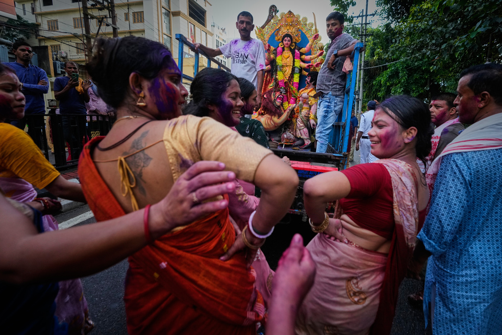 Devotees with color-smeared faces dance on a road during a procession for immersion of an idol of Hindu goddess Durga in Guwahati, Thursday, Oct. 2, 2025. (AP Photo/Anupam Nath)