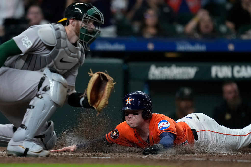 Houston Astros' Nick Allen scores behind Athletics catcher Jonah Heim during the fifth inning of a baseball game Friday, Aug. 21, 2026, in Houston. (AP Photo/Kevin M. Cox)