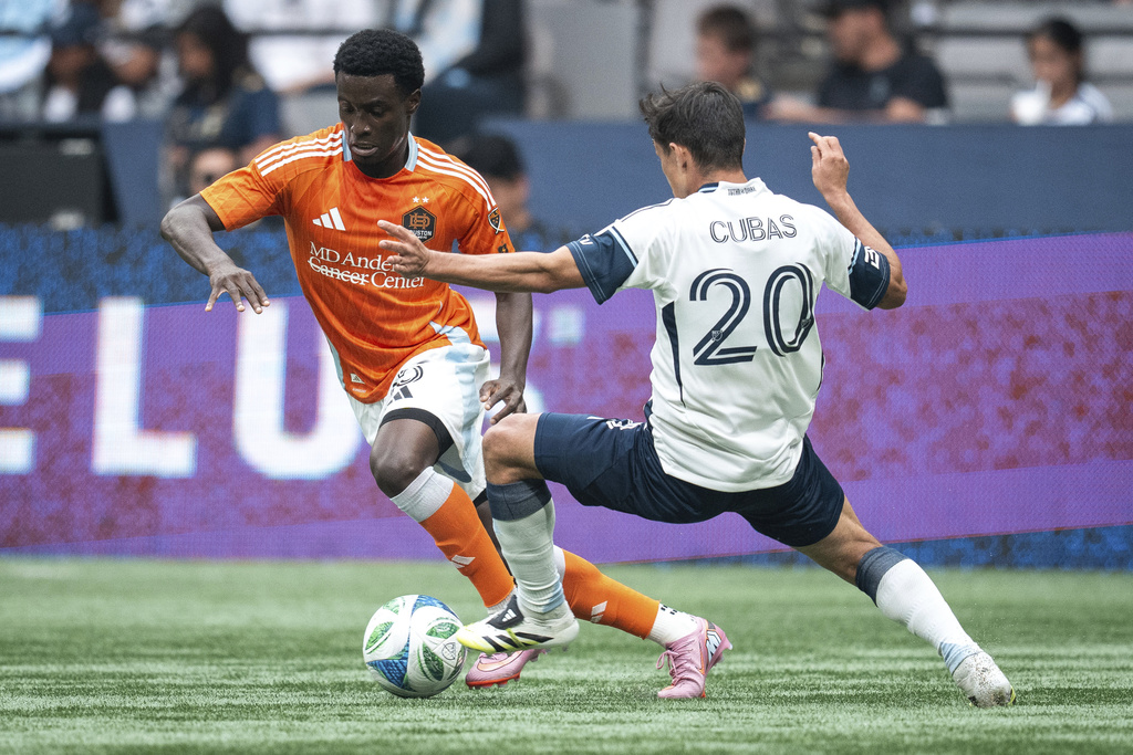Houston Dynamo's Brooklyn Raines runs past Vancouver Whitecaps' Andres Cubas (20) during the first half of an MLS soccer match in Vancouver, British Columbia, Sunday, Aug. 17, 2025. (Ethan Cairns/The Canadian Press via AP)